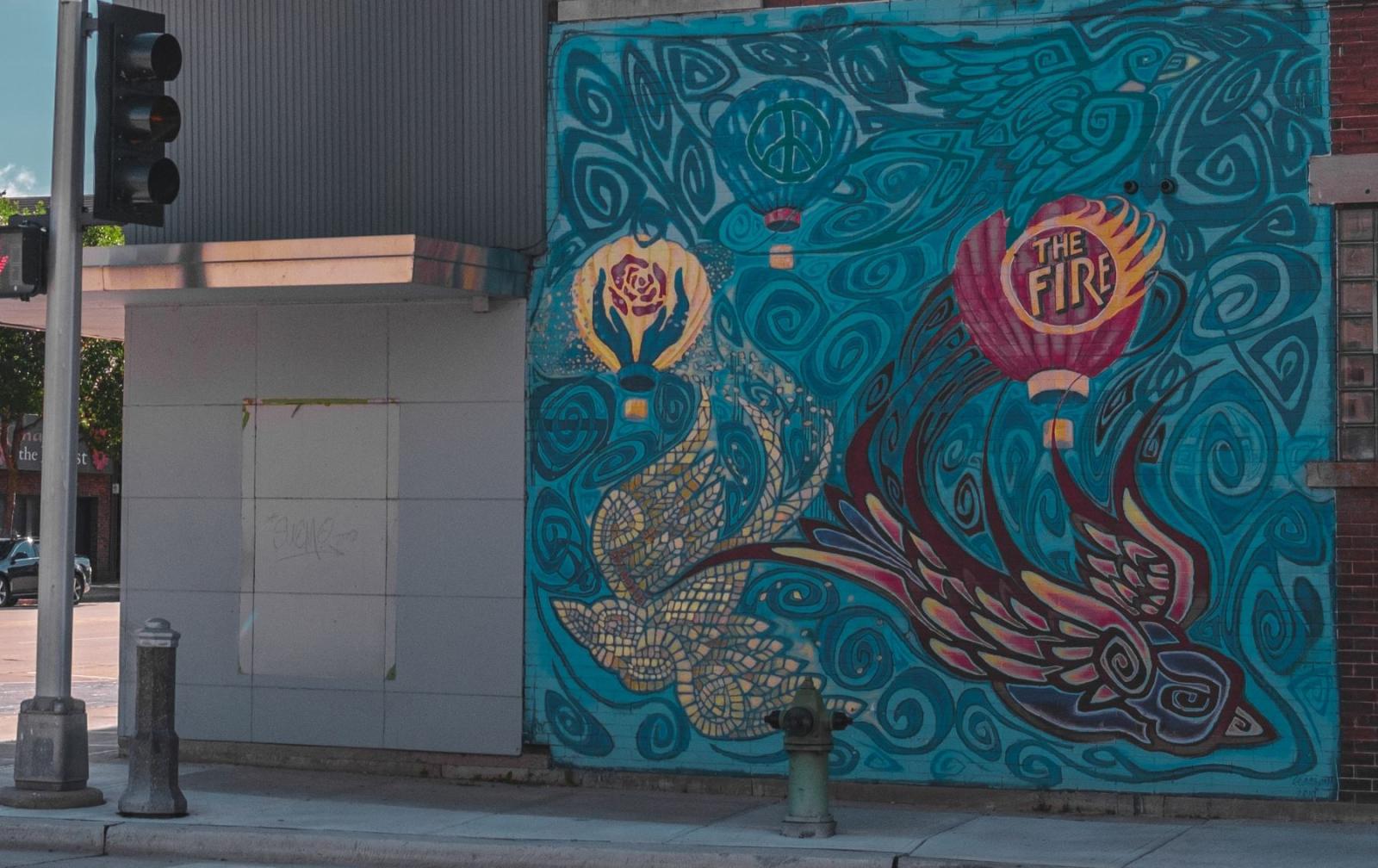 mural with various designs on a vibrant blue background, and the words "The Fire" standing out of a torched flame