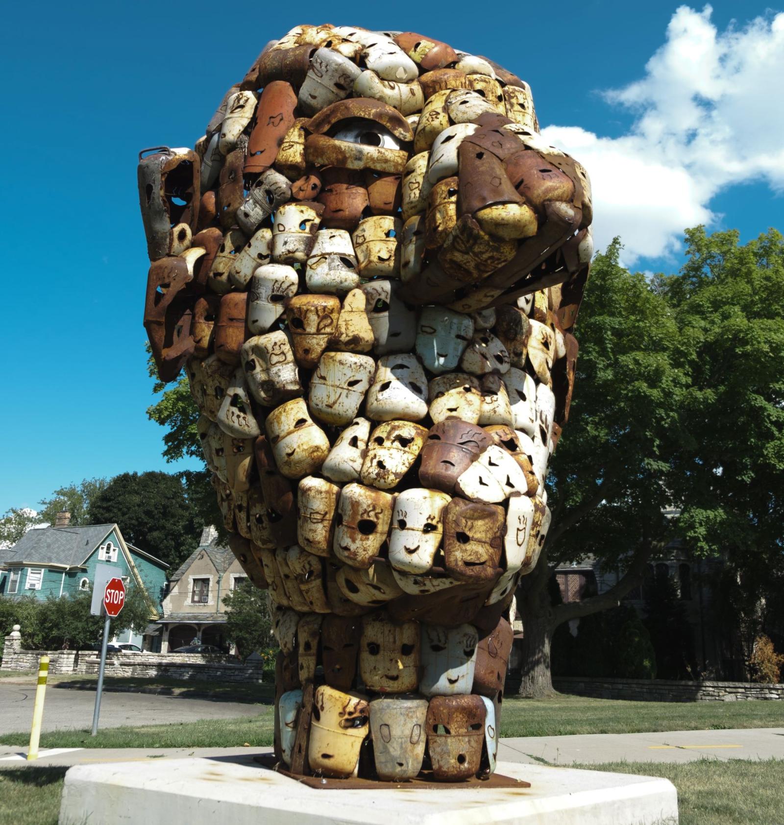 sculpture of a face made up of rusted faces