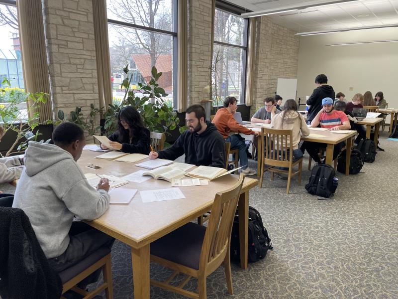 History students looking at documents from the Archives at tables near the windows.