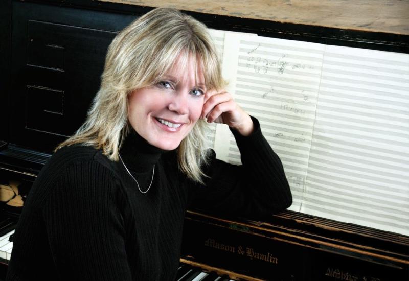 Patty Darling, jazz improv faculty, sitting at a piano with the beginnings of a composition on sheet music.