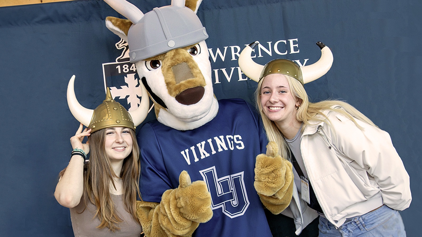 Prospective students with horned Viking helmets on pose with Blu, the Lawrence mascot