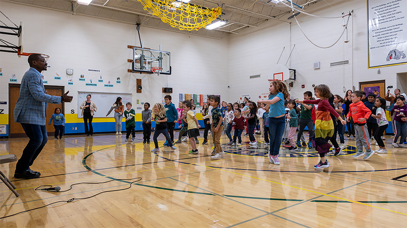 Robert Battle leads a group of young students in a dance in the Badger Elementary gym.