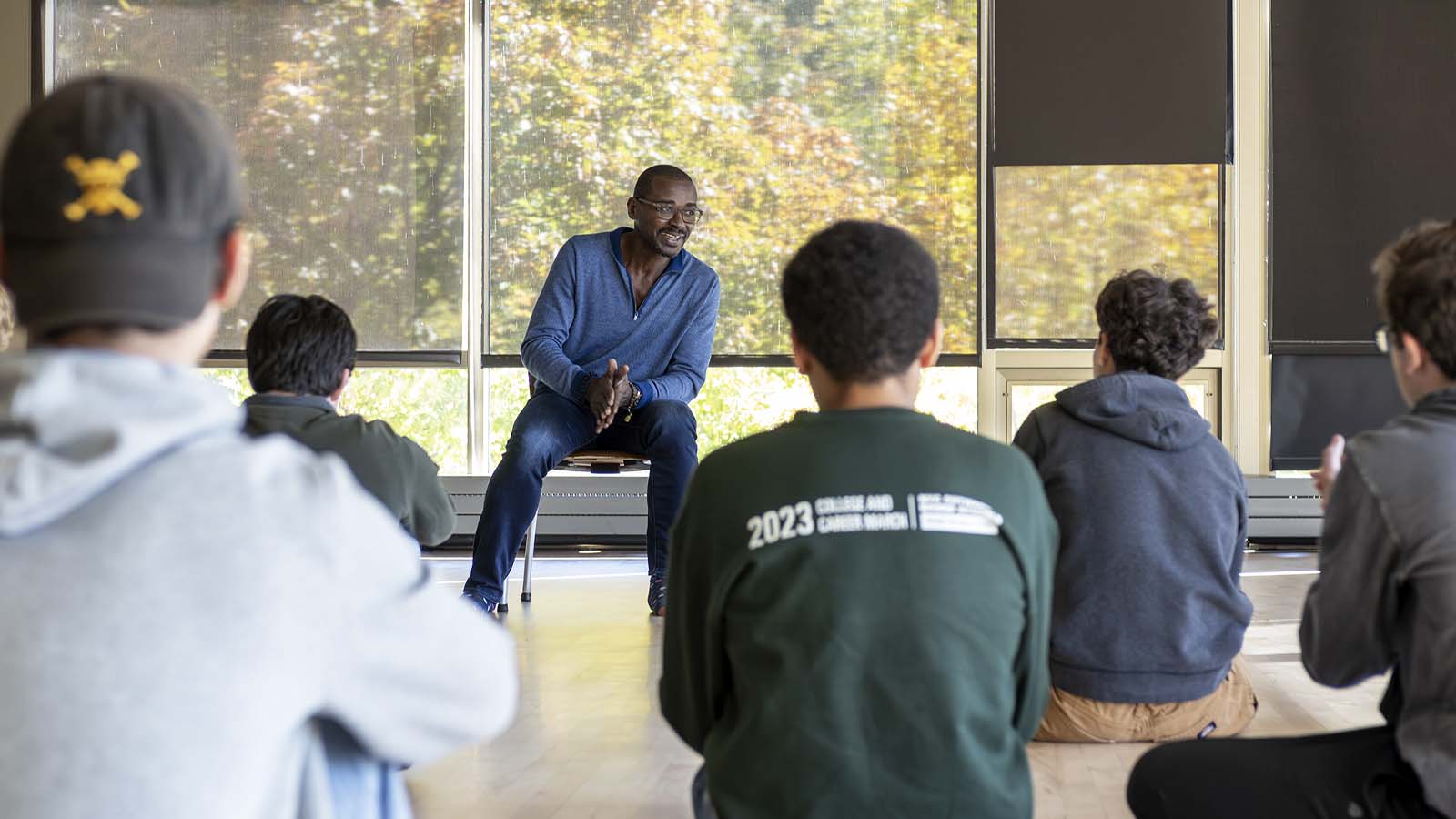 Robert Battle sits in front of a window and speaks to a group of students.