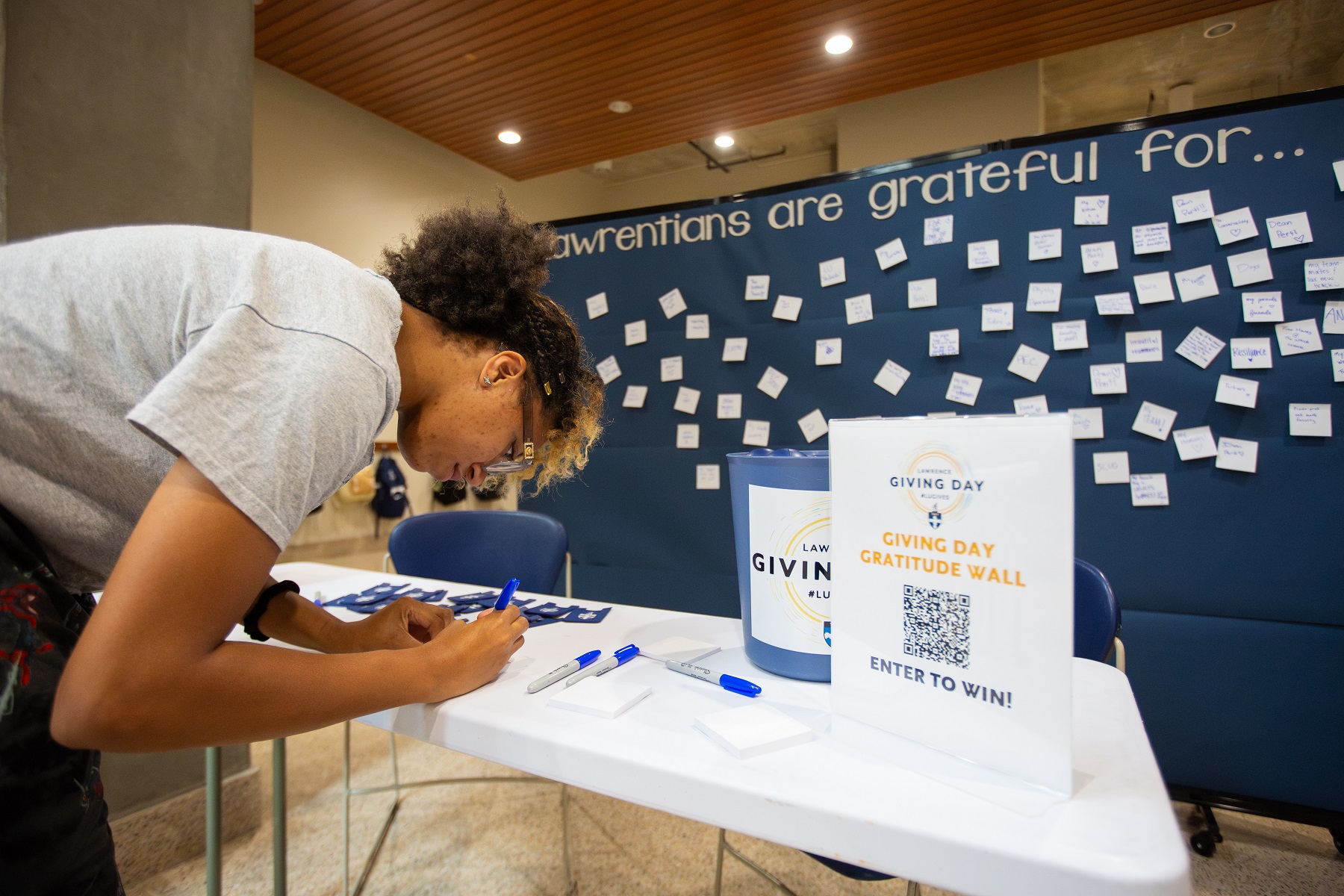 Students write messages on a gratitude wall in Warch Campus Center during Giving Day..