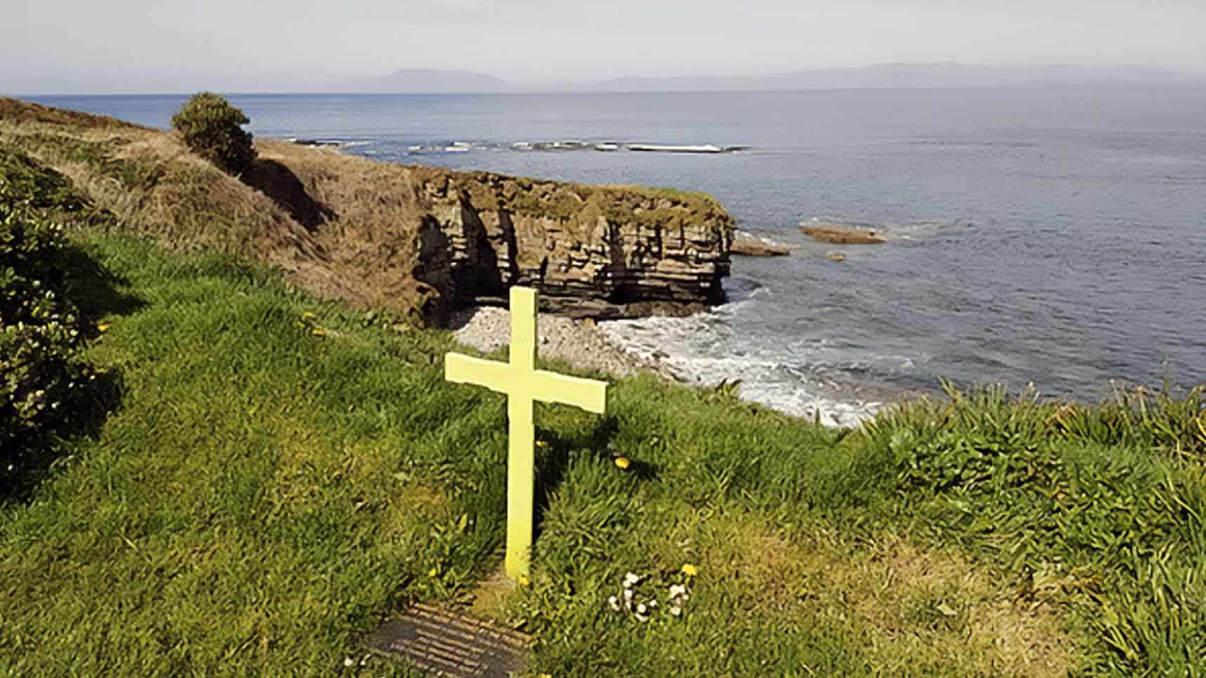 Cross on grassy cliff on shores of Ireland