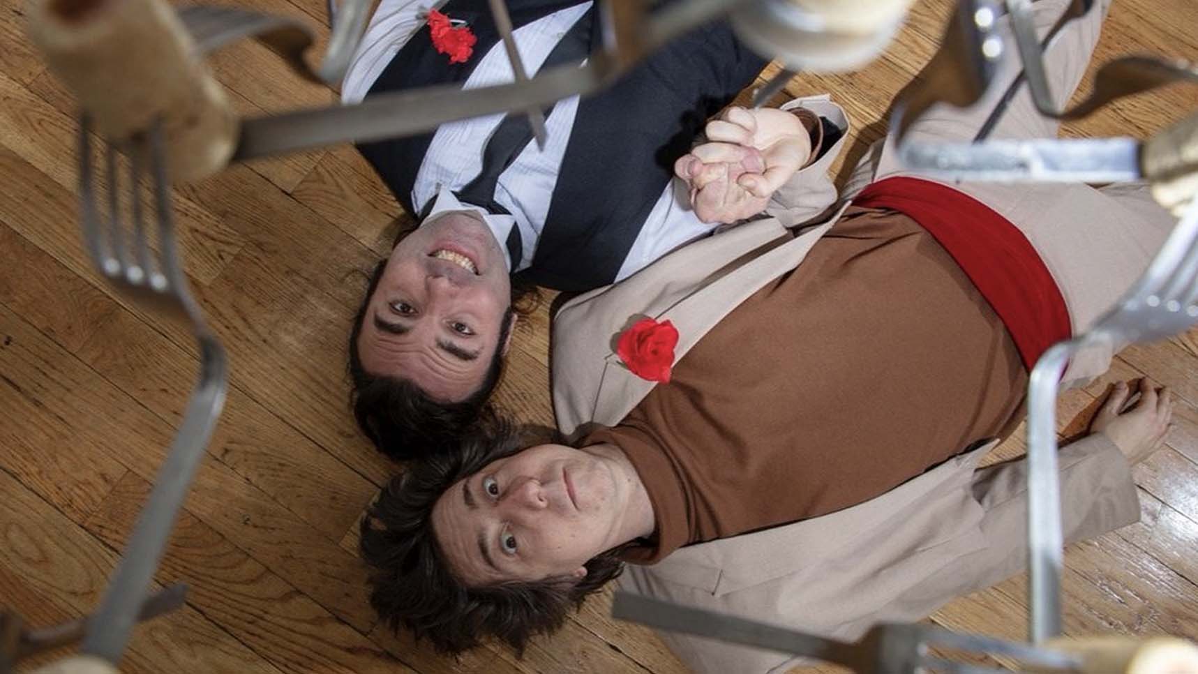 Two people laying on floor and looking up at forks and corks floating in the air