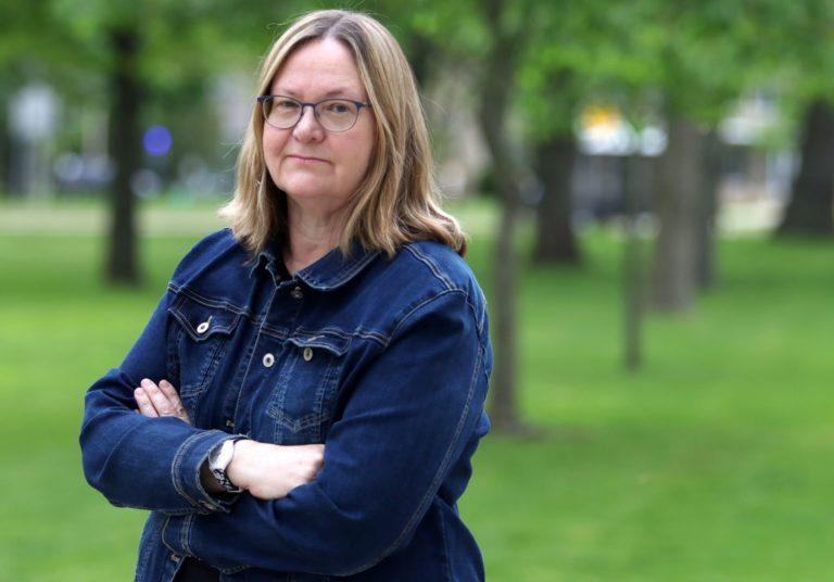 Claudena Skran, standing with her arms crossed in a jean jacket, stands on Main Hall Green.