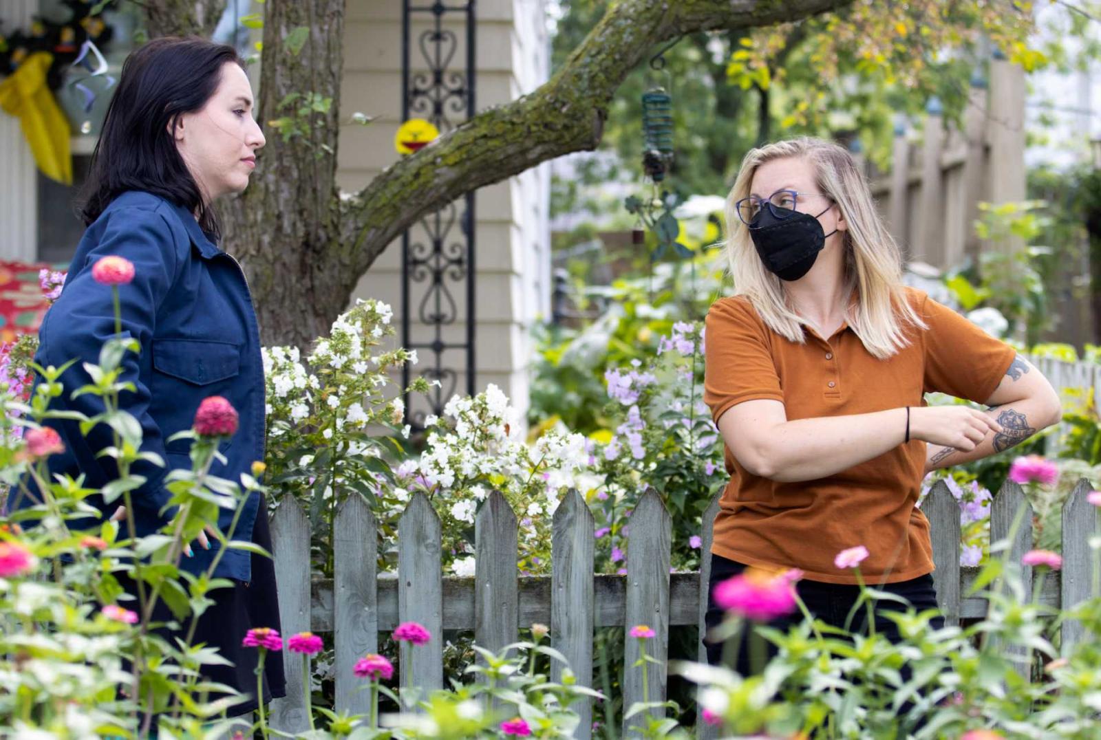 Molly Preston '10 talks to a cast member. They are surrounded by blooming flowers.