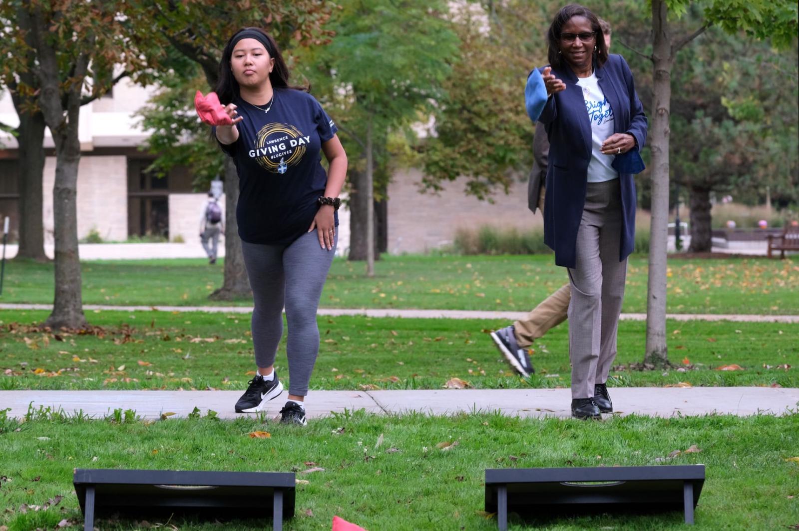 Lawrence student and the university president, Laurie Carter, toss blue and pink bean bags.