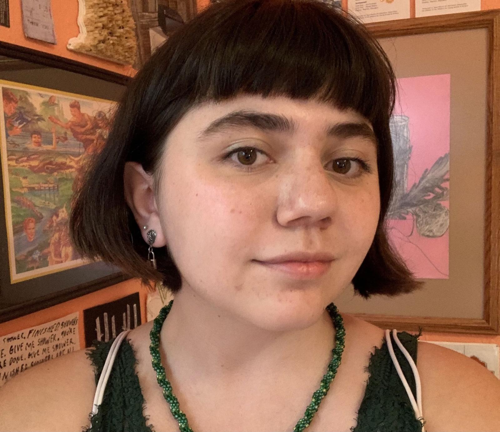 Head shot of Emma Goodman with her art in the background.