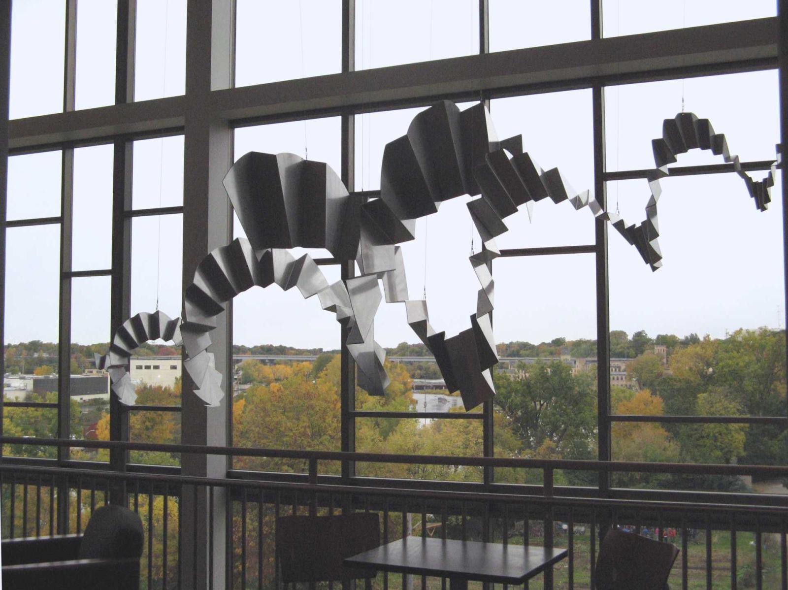 Interlocking spirals of crimped metal hanging in front of large windows. 