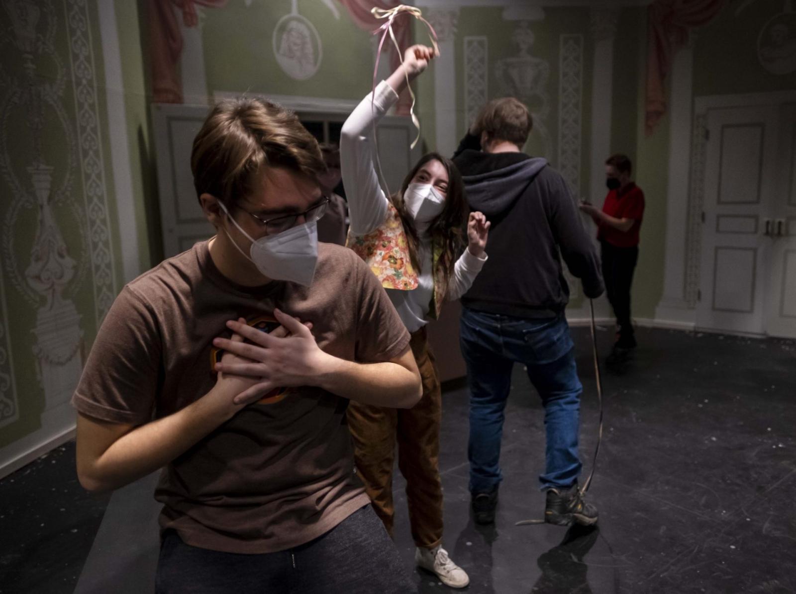 Student holds both hands over chest while another student behind them throws ribbons at them.