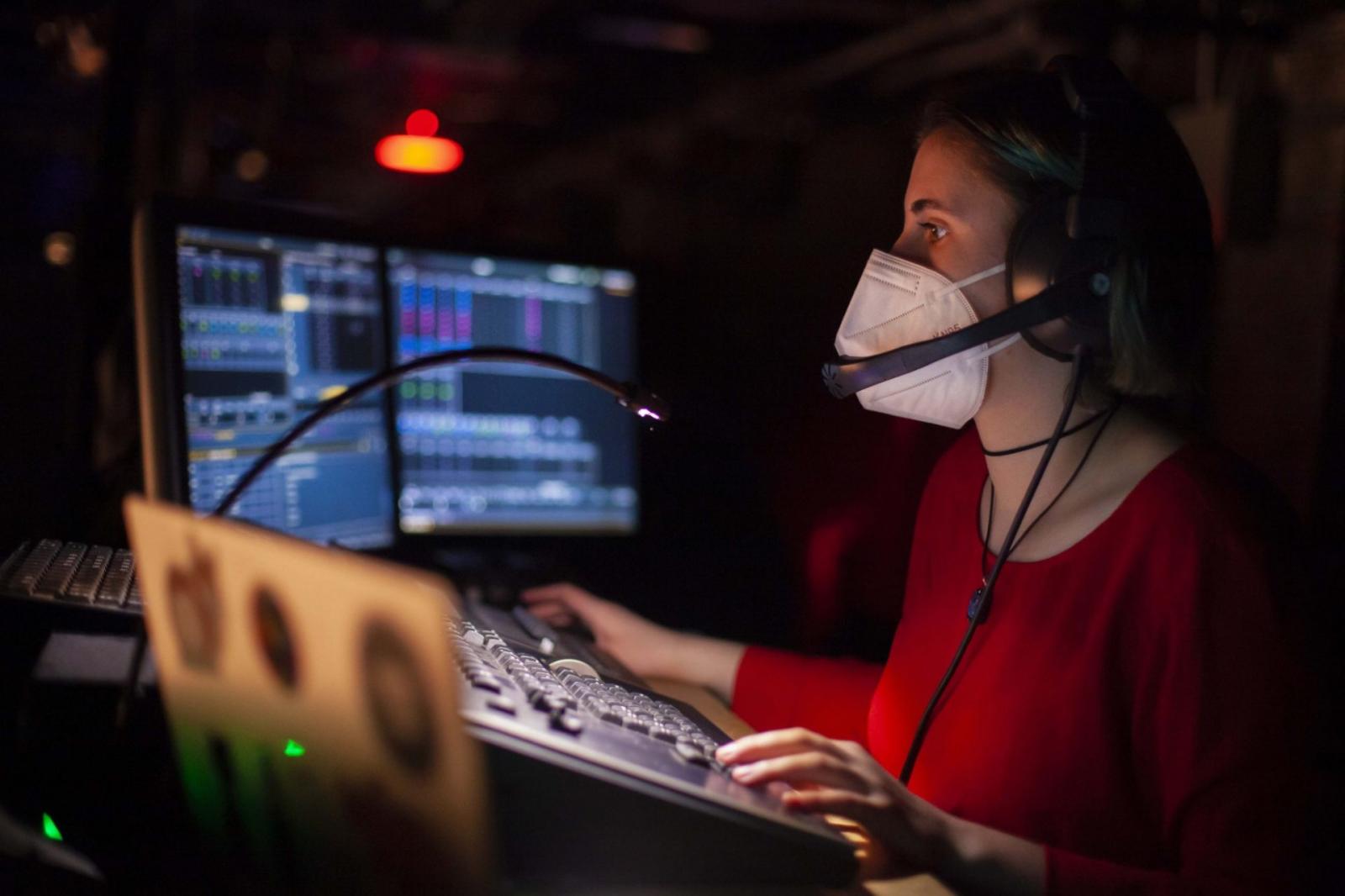 Student wearing headphones adjusts the light board 