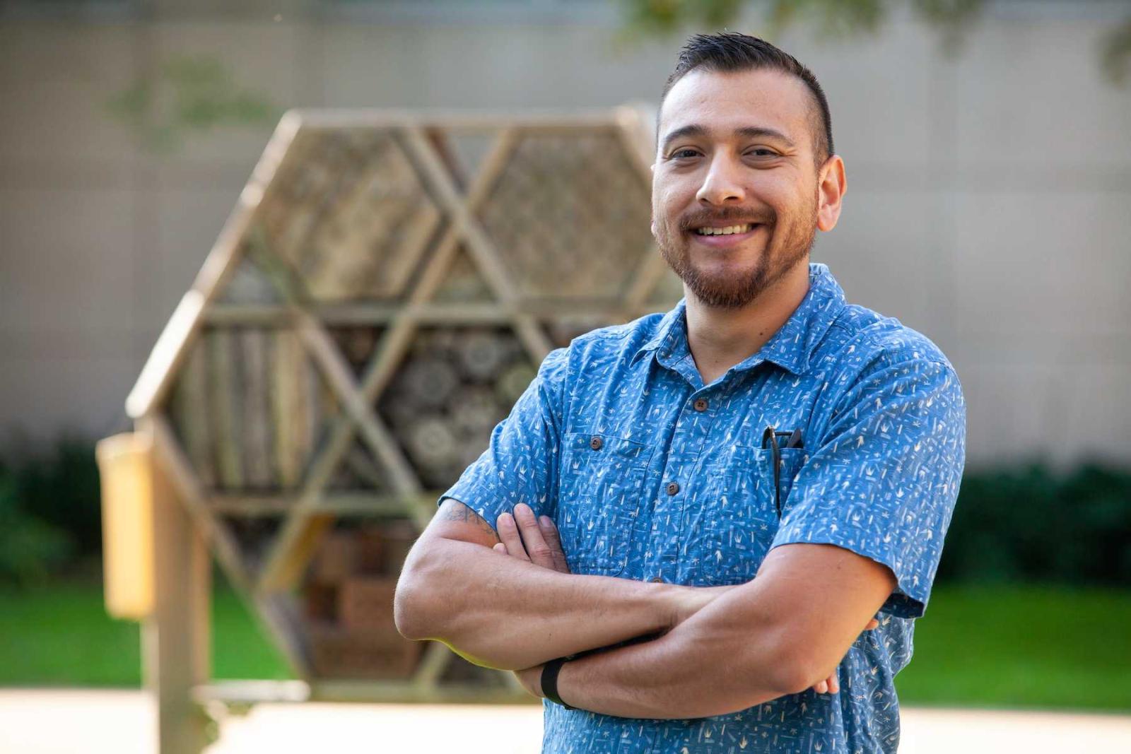 Israel Del Toro poses in front of a bee house on campus.