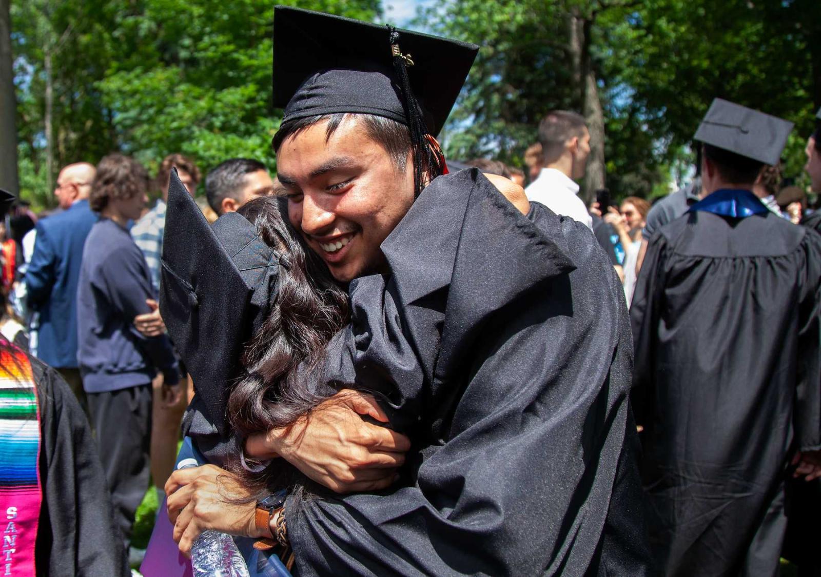 Graduates hug following the commencement ceremony.