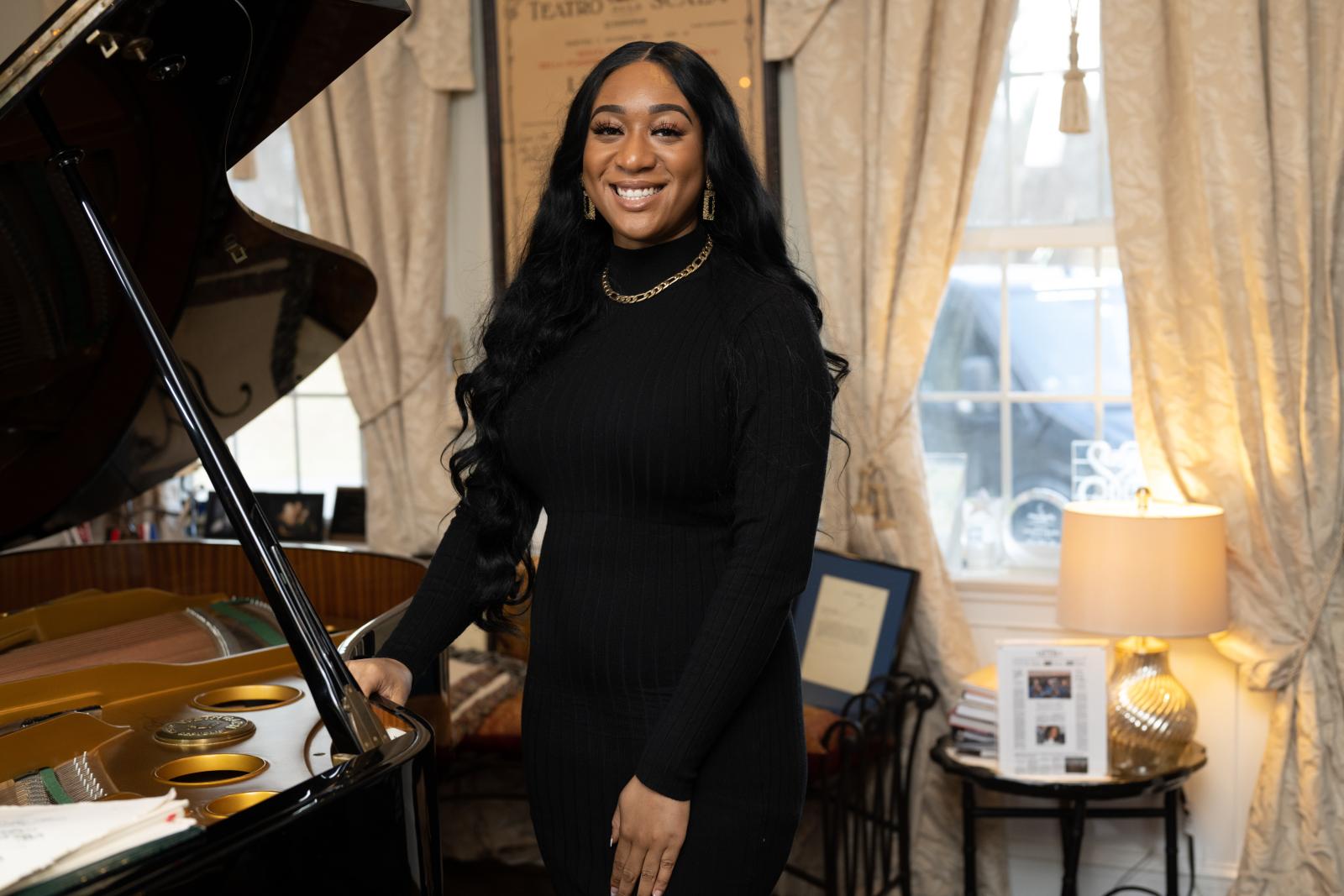 Portrait of Hannah Jones standing next to a piano.