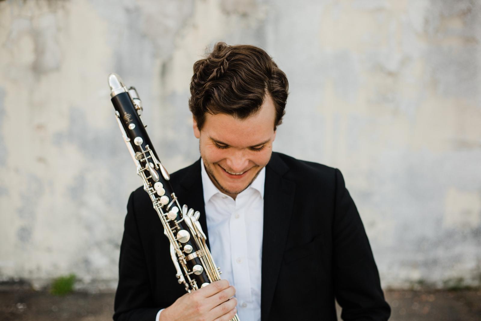 Andy Hudson looks down as he holds a clarinet