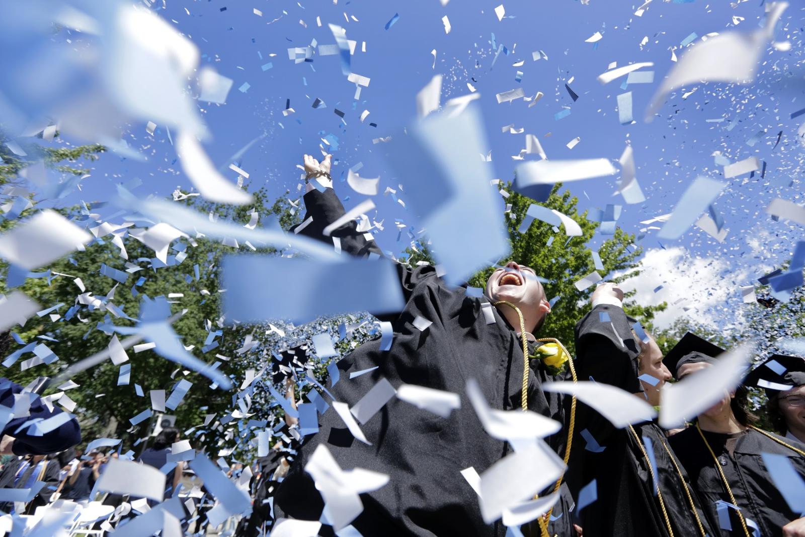 Confetti and graduation caps fly as graduates celebrate at the close of Commencement.