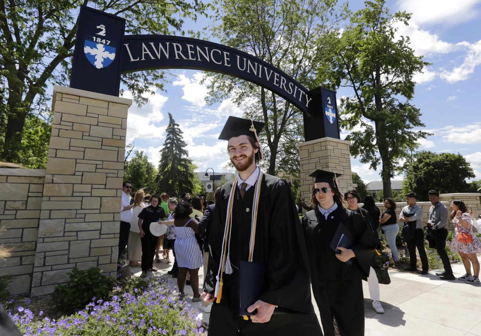 Graduate Evan Ney smiles as he walks through the Lawrence Arch following Commencement.