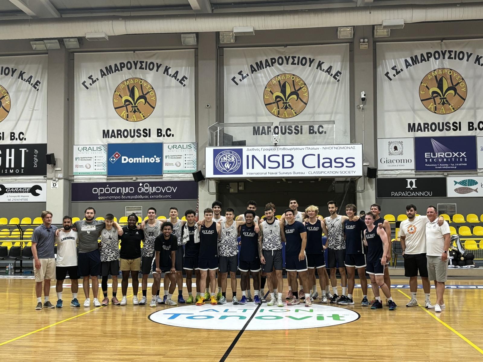 Players, coaches, and parents pose for a photo in a gym in Greece.