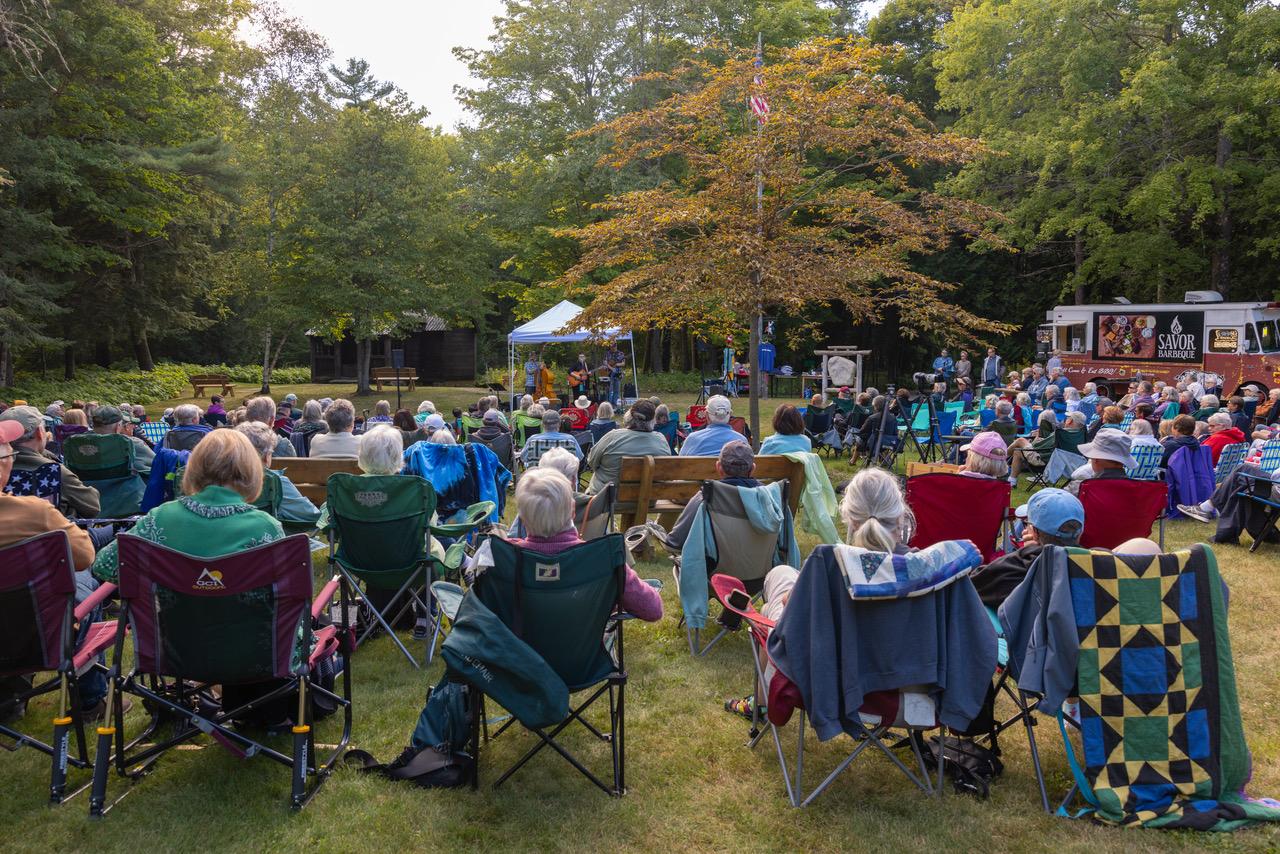 a crowd gathers in front a musicians performing under a tent