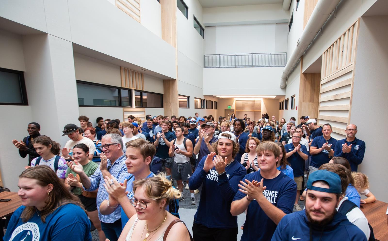 Students and staff applaud at the ribbon cutting.