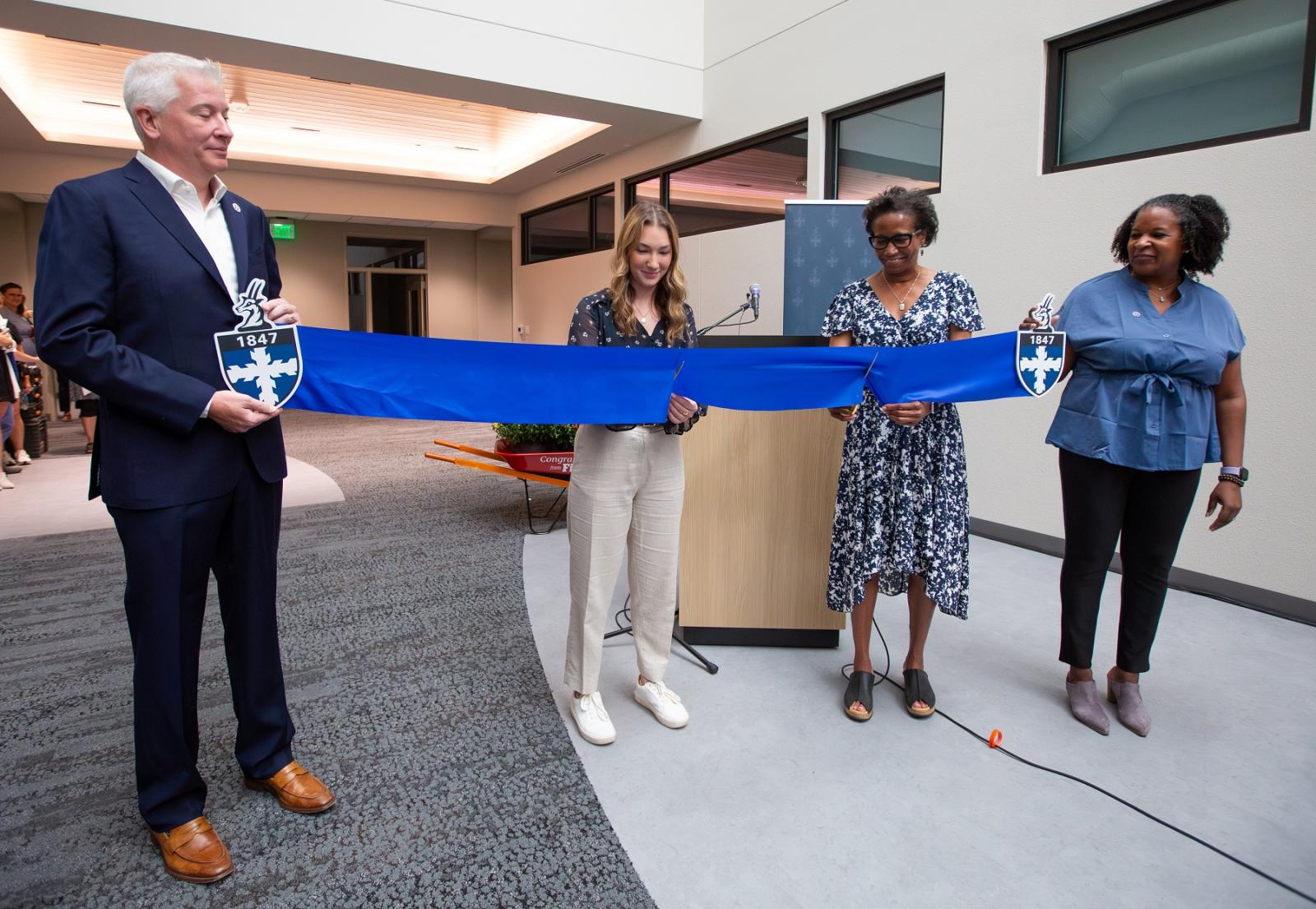 President Laurie A. Carter and senior Mattigan Haller cut the ribbon as Christyn Abaray and Chris Clarke look on.