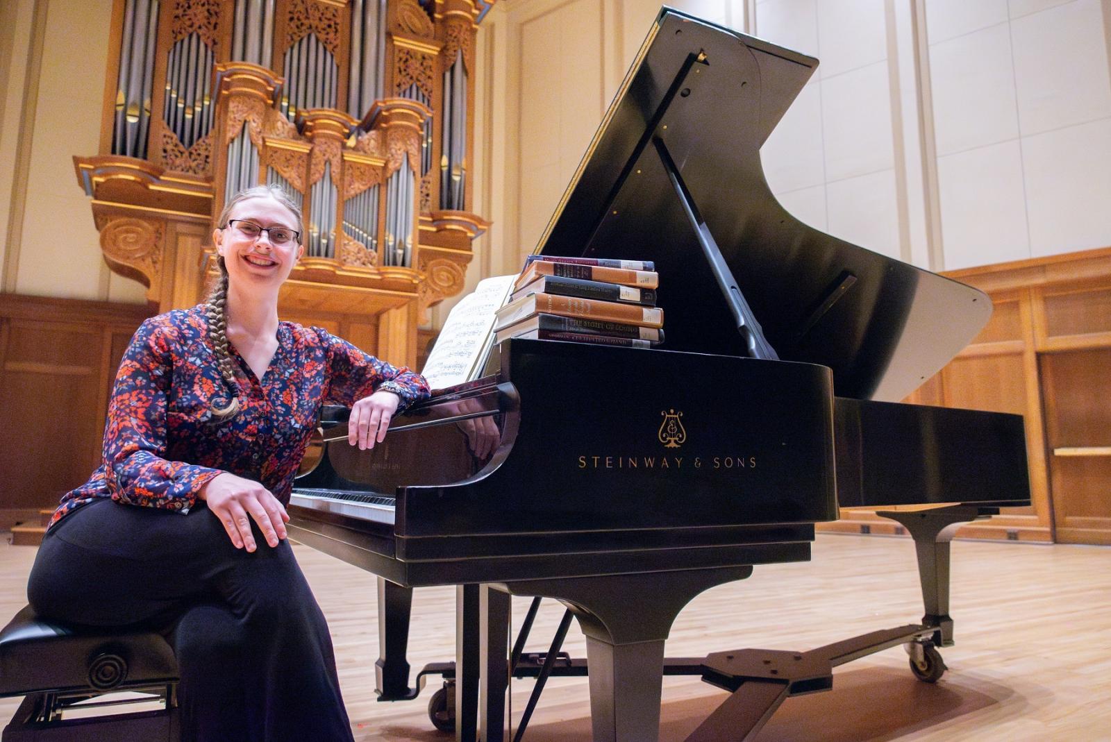 Senior Helen Panshin sits at the piano on the stage of Memorial Chapel with some of the musicology textbooks.