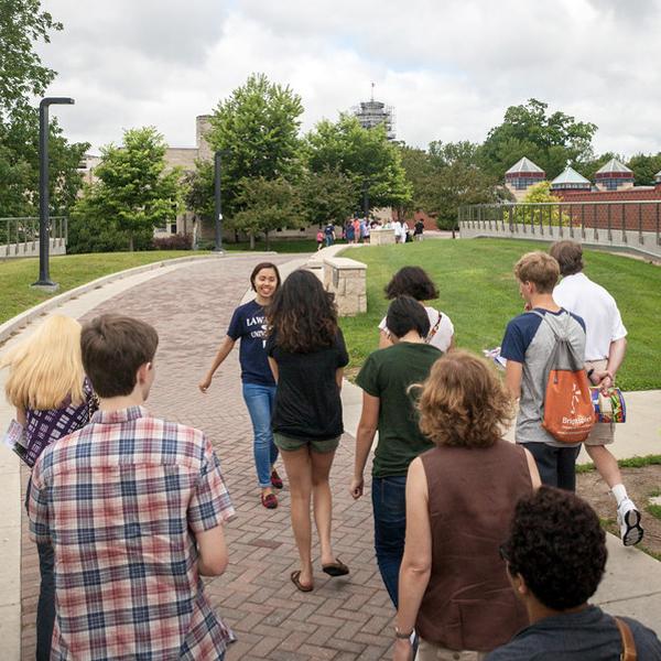 Prospective students receiving a tour from an Admissions tour guide crossing over the bridge