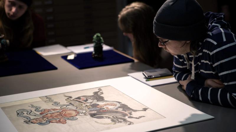 Student studying a painting on a table in museum studies class