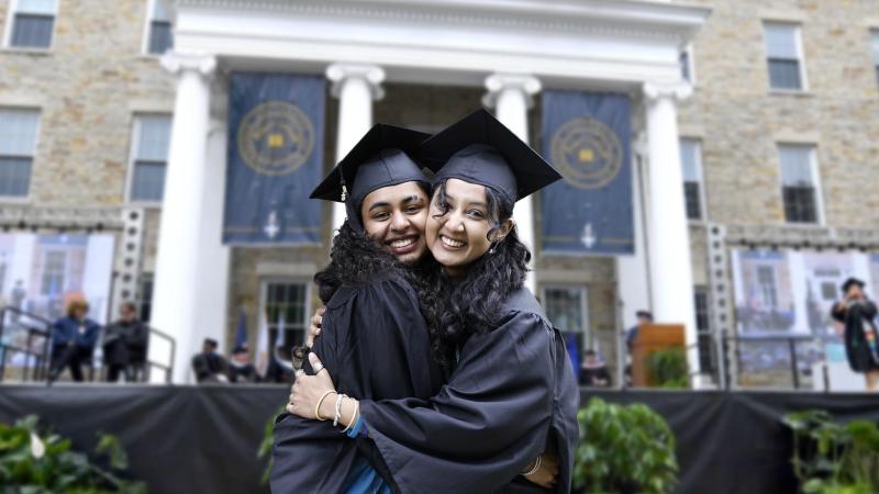 Two students embracing on graduation day in front of Main Hall