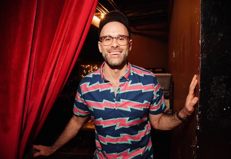 Asher Perlman looks out from behind a stage curtain.