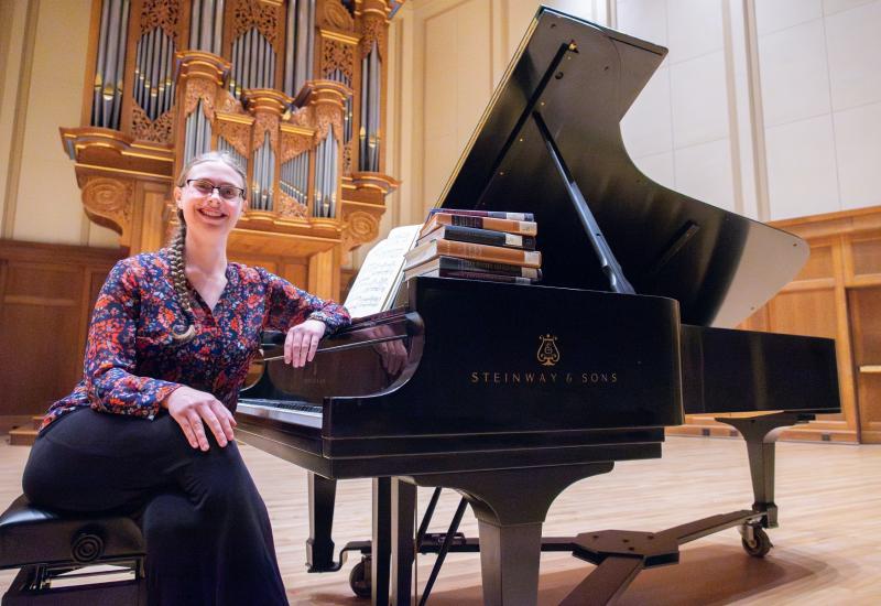 Senior Helen Panshin sits at the piano on the stage of Memorial Chapel with some of the musicology textbooks.