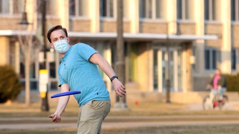 Student throws a frisbee on Main Hall Green