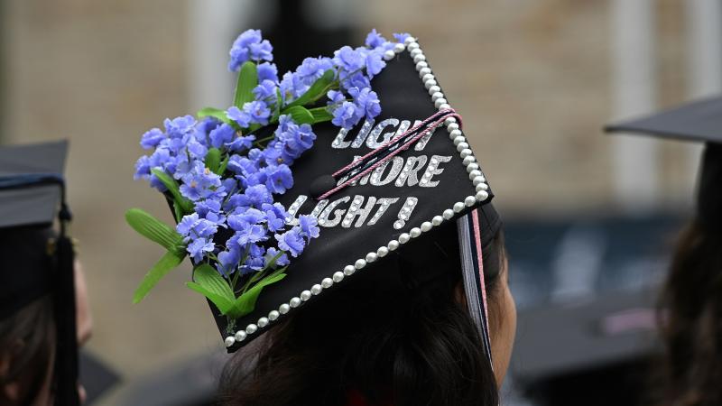A graduation cap is adorned with Light More Light!