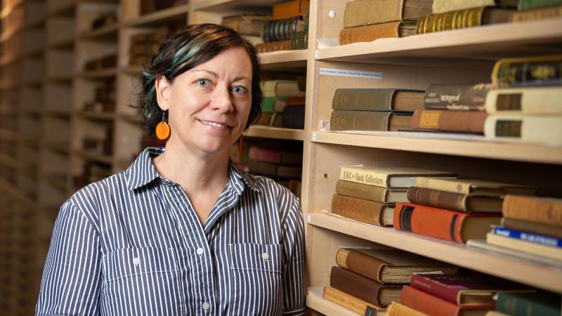 Beth Zinsli poses for a photo with books from the Richmond Rare Book Collection.