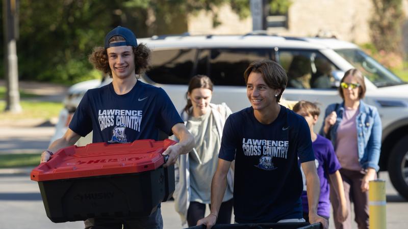 Students push carts and carry bins for move-in.