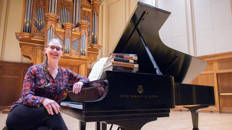 Senior Helen Panshin sits at the piano on the stage of Memorial Chapel with some of the musicology textbooks.