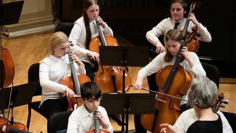 A small group of young musicians playing cello.
