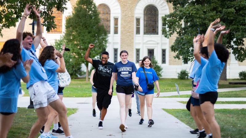 Upperclass students line the sidewalk to welcome first-year students to campus.