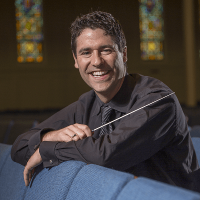 Dr. Matthew Arau headshot with conductor baton in the Lawrence Memorial Chapel