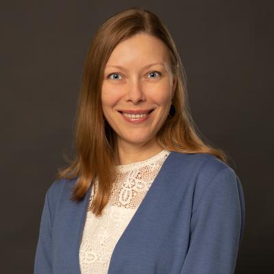 The photo picturing a head portrait of a white Slavic woman in her late 30s smiling at the camera