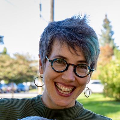 Big grin. Glasses. Tufty hair. Hoop earrings jauntily moving. 