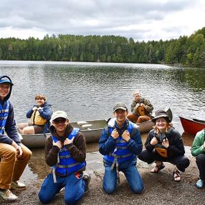 Group shot of students on shore by canoes - 2024 Land and Sea Pre-orientation Experience