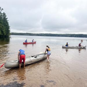 Six students canoeing on the lake near shore - 2024 Land and Sea Pre-orientation Experience